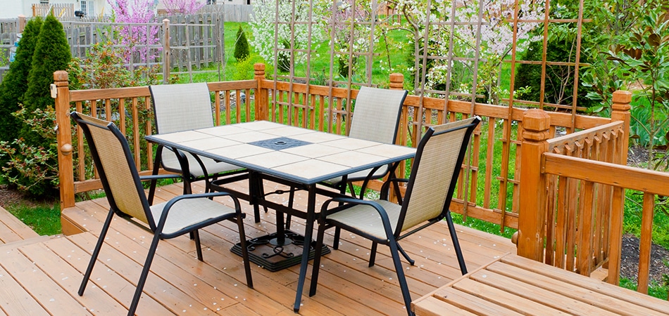 Timber deck with a table and chairs beside a garden fence