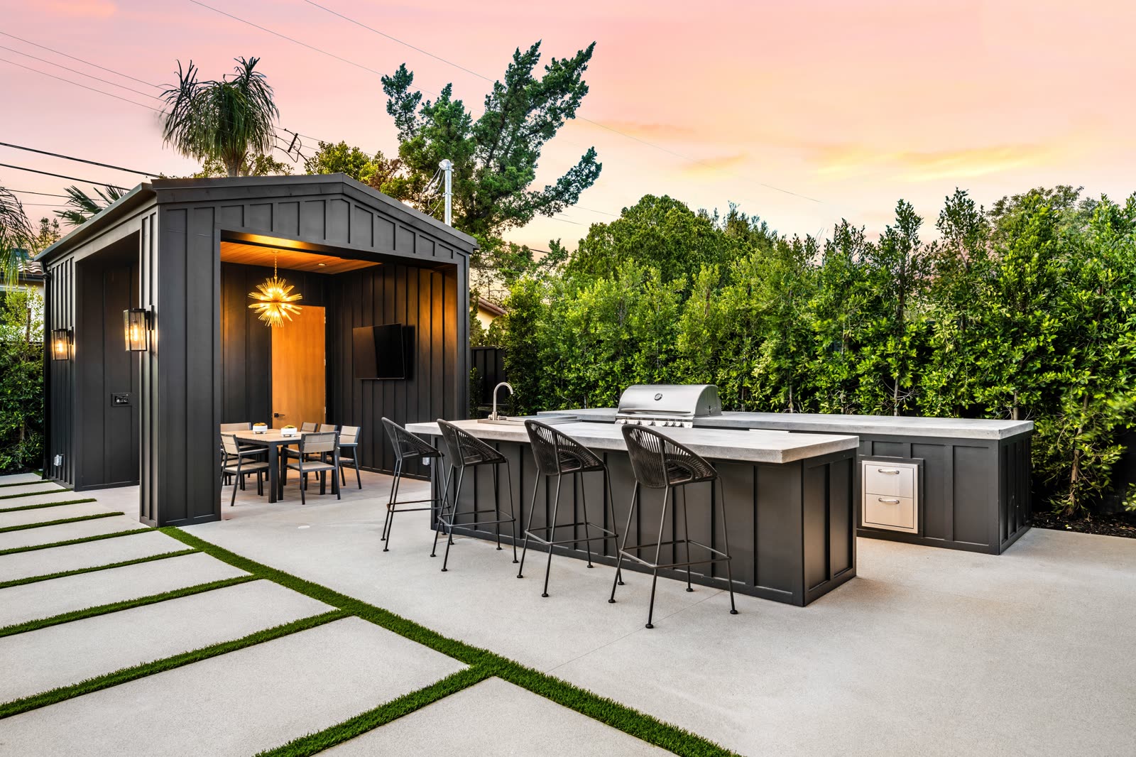 Modern outdoor kitchen island with bar seating under a twilight sky