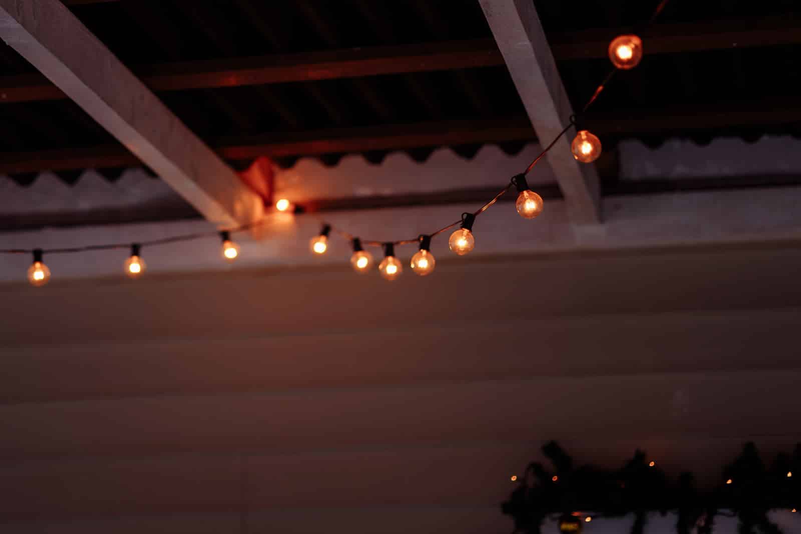 String lights strung under a covered porch roof after dark