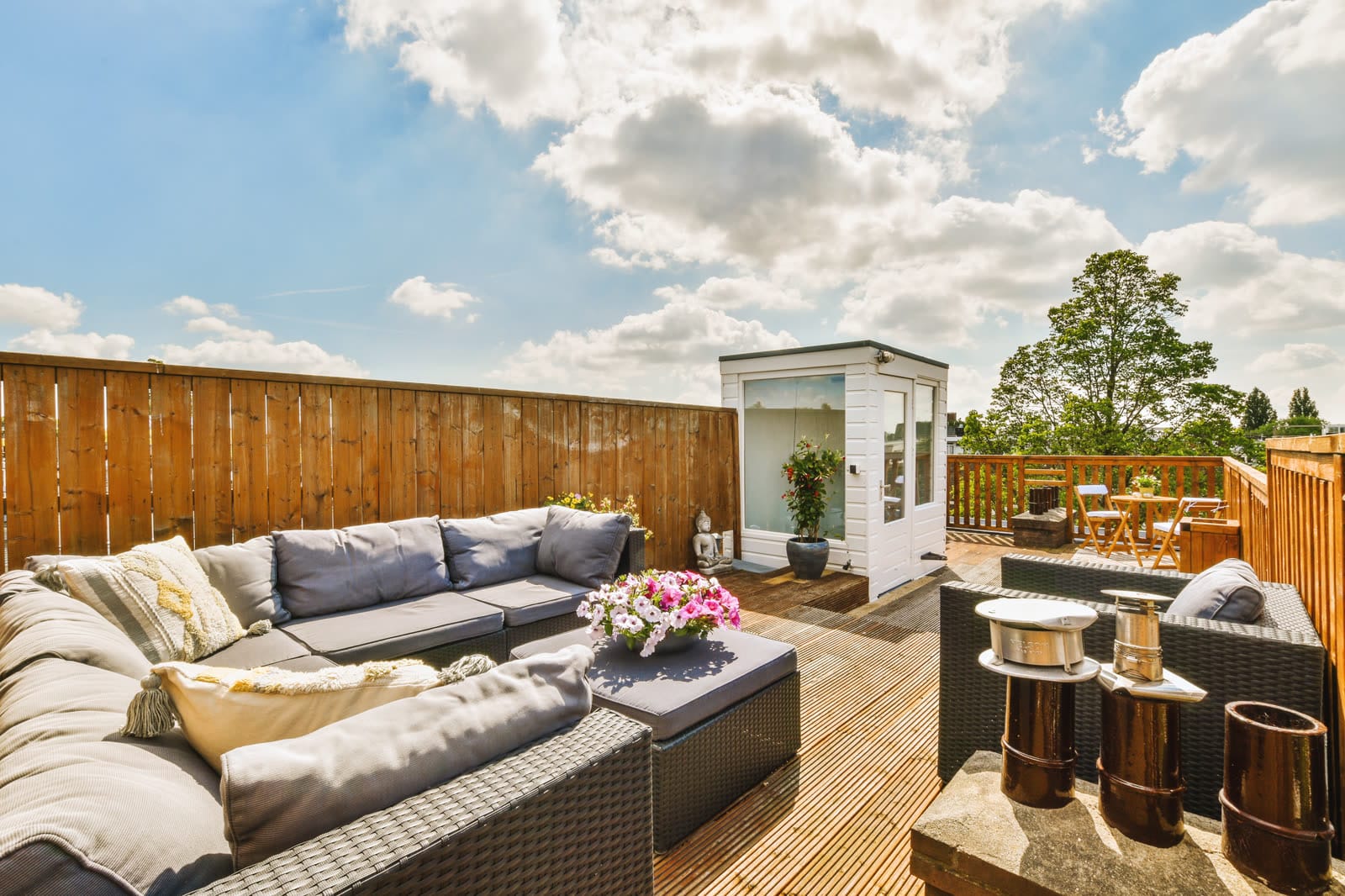 Grey sectional seating and a fire table on a paved patio