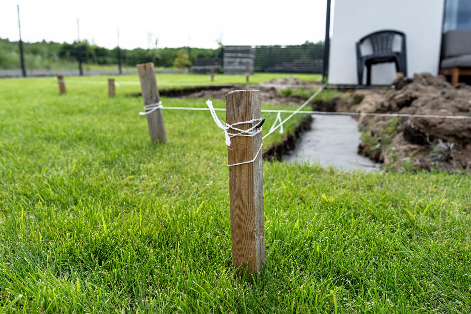 Timber stakes and string lines setting out a foundation trench in a lawn