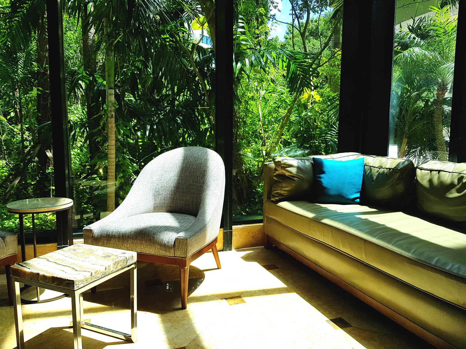 Screened sunroom with a daybed looking out onto dense tropical planting