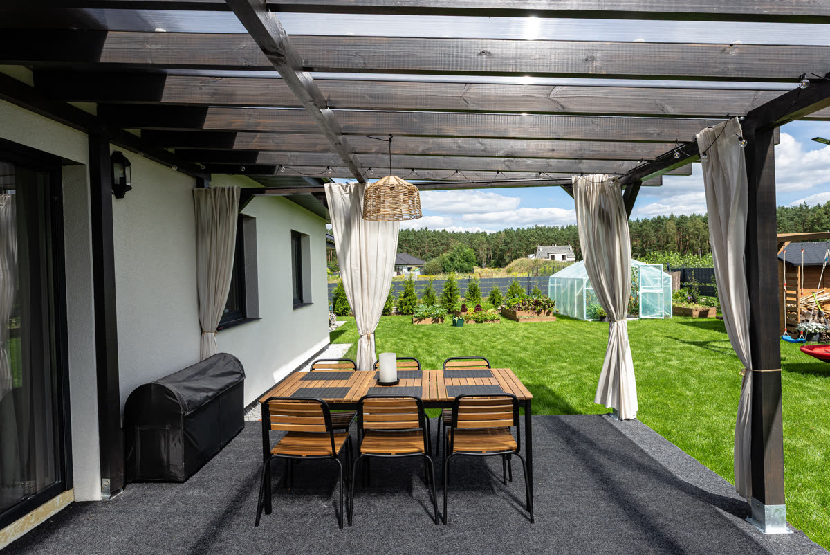 Covered patio with drawn curtains and a long dining table