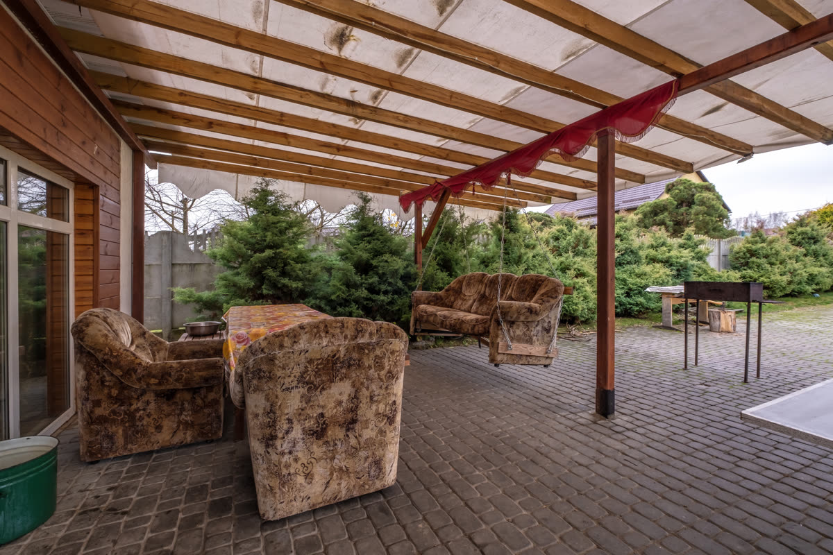 Covered patio with timber posts looking out onto dense planting
