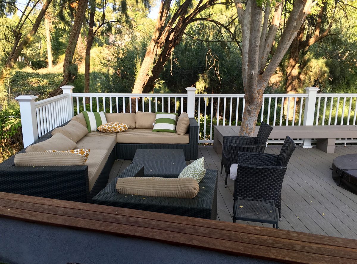 Wicker sofa and armchairs on a covered patio beside a green lawn