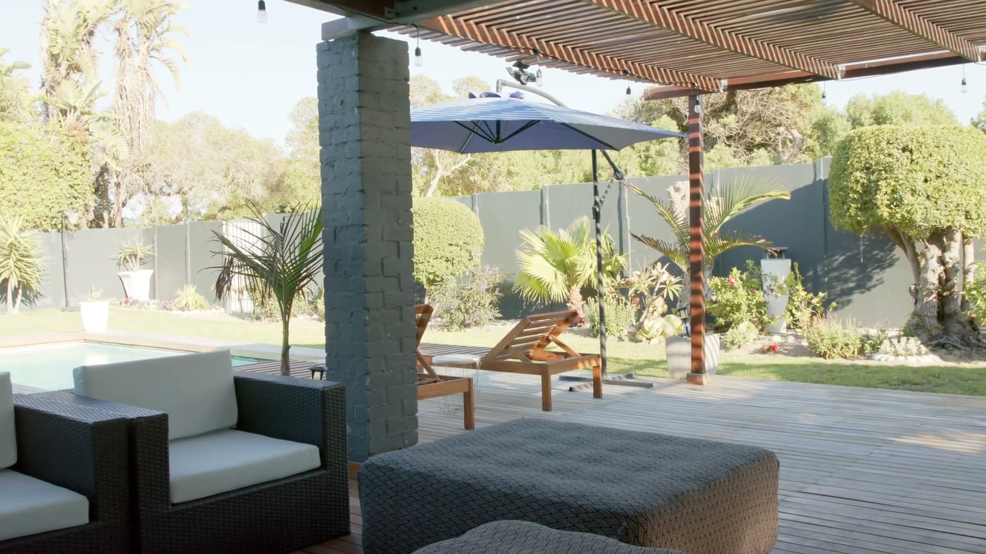 Covered patio seating under wide umbrellas beside planting