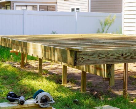 New wooden deck frame under construction in a fenced backyard
