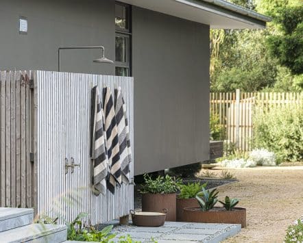 Outdoor shower with a wood enclosure on the side of a house