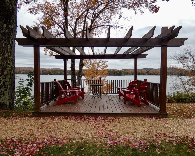 Wooden pergola built over a deck with red lawn chairs